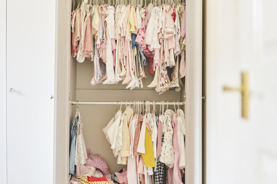 An open wardrobe filled with various children's clothes neatly hanging