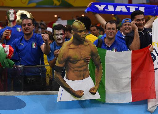 Fans hold a cardboard cut out of Mario Balotelli and their national flag as they celebrate after Italy beat England at the Amazonia Arena in Manaus during the FIFA World Cup on June 14, 2014