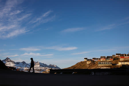 A man walks along the road in the evening sunshine through the town of Tasiilaq, Greenland, June 17, 2018. REUTERS/Lucas Jackson