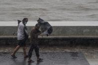 Two men carrying umbrellas walk on the Marine Drive under heavy rain in Mumbai on June 3, 2020. (Photo by PUNIT PARANJPE/AFP via Getty Images)