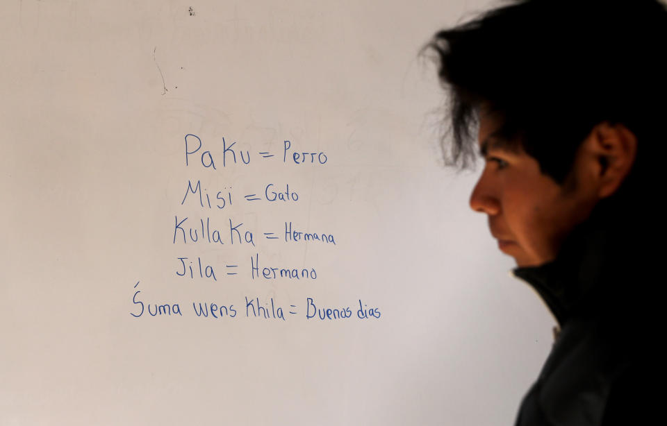 Jose Choque stands next to his work that he wrote on a dry erase board during a Uru language lesson, in a classroom in the Urus del Lago Poopo indigenous community, in Punaca, Bolivia, Monday, May 24, 2021. The last native speakers gradually died and younger generations grew up schooled in Spanish and working in other, more common Indigenous languages, Aymara and Quechua. To save their identities, the Urus are trying to revive their native language. (AP Photo/Juan Karita)