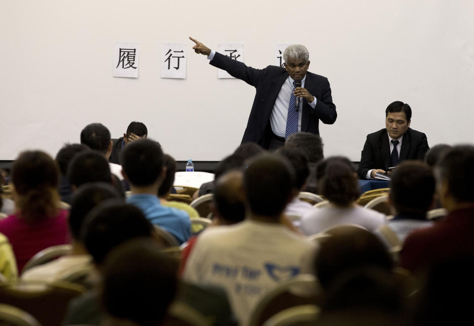 Bala Chandran Tharman, deputy chief of mission at the Malaysian embassy in Beijing speaks to relatives of Chinese passengers onboard the Malaysia Airlines MH370 during a briefing at a hotel in Beijing, China Saturday, April 26, 2014. A number of Chinese relatives still aren't accepting the theory that the plane crashed in the Indian Ocean. They're insisting that Malaysian officials haven't told them the truth. The Chinese characters on the wall reads: "Meet the commitment." (AP Photo/Andy Wong)