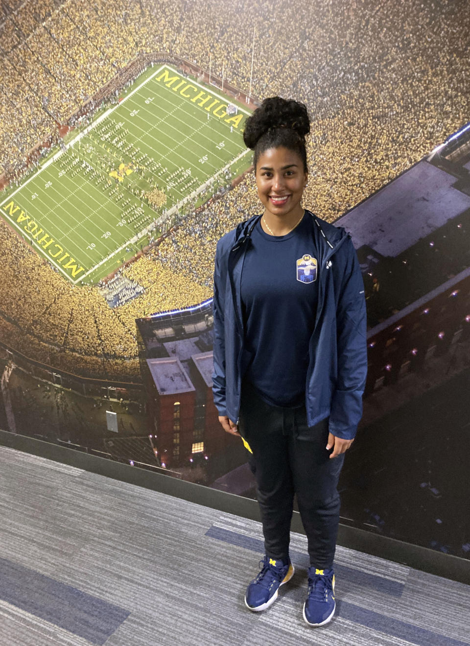 Michigan's Mimi Bolden-Morris, the first female graduate assistant football coach at Power Five school since the late 1980s, poses for a photo in front of a mural of Michigan Stadium, on Dec, 15, 2022, in Ann Arbor, Mich. (AP Photo/Larry Lage)