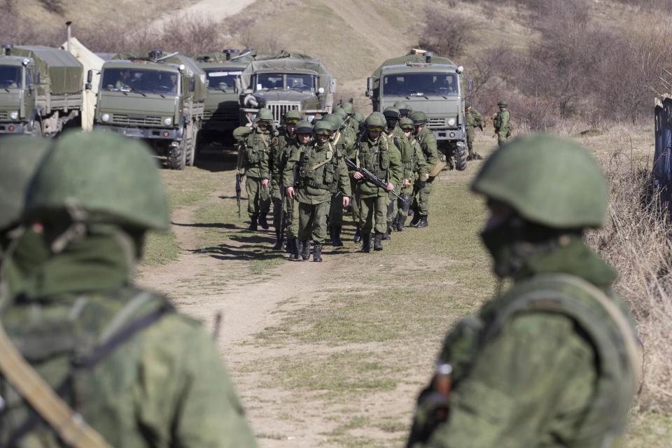 Military personnel, believed to be Russian servicemen, walkoutside the territory of a Ukrainian military unit in the village of Perevalnoye outside Simferopol