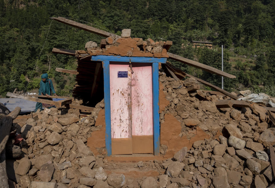 A survivor clears debris as she tries to recover goods from earthquake damaged house in Rukum District, northwestern Nepal, Monday, Nov. 6, 2023. The Friday night earthquake in the mountains of northwest Nepal killed more than 150 people and left thousands homeless. (AP Photo/Niranjan Shrestha)