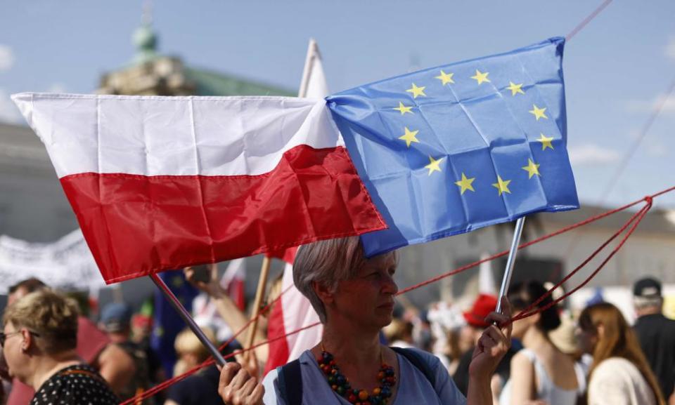 A woman holds the Polish and the European flag at the anti-government demonstration, in front of the presidential palace.