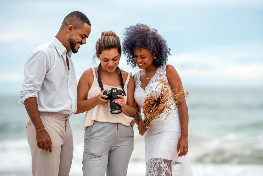A wedding photographer shows a bride and groom their photos. 