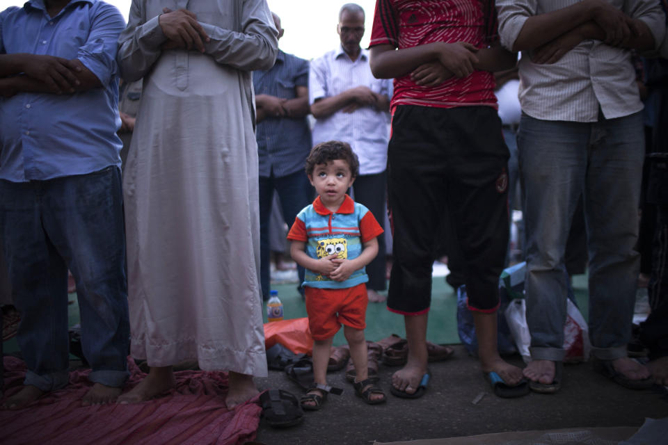 An Egyptian child attends prayers with his father at a protest near Cairo University in Giza, Egypt, Thursday, August, 1, 2013. (AP Photo/Manu Brabo)