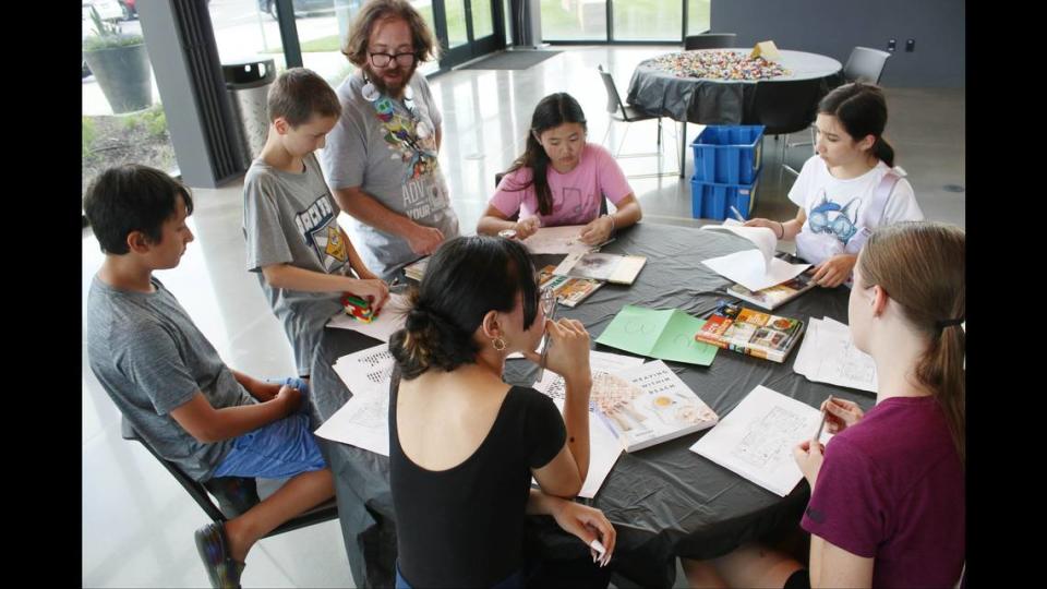 Tommy Govert, children program specialist at the Olathe Library, helps the group work on making their own Morse code messages during a dystopia survival skills program.