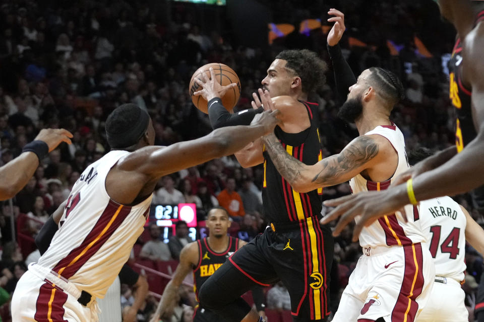 Atlanta Hawks guard Trae Young, center, drives to the basket as Miami Heat center Bam Adebayo, left, and forward Caleb Martin, right, defend during the first half of an NBA basketball game Friday, Dec. 22, 2023, in Miami. (AP Photo/Lynne Sladky)