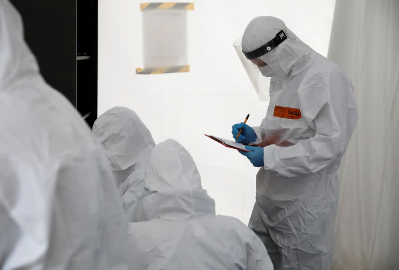 FILE PHOTO: A man wearing a protective coverall fills up the form before performing tests for the coronavirus disease (COVID-19) at a drive-thru testing centre in Warsaw