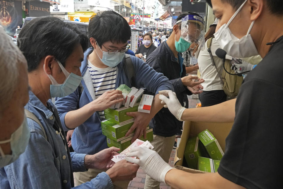 FILE - People wearing face masks, purchase COVID-19 antigen test kits at a market in Hong Kong on March 5, 2022. The fast-spreading omicron variant is overwhelming Hong Kong, prompting mass testing, quarantines, supermarket panic-buying and a shortage of hospital beds. Even the morgues are overflowing, forcing authorities to store bodies in refrigerated shipping containers. (AP Photo/Kin Cheung, File)