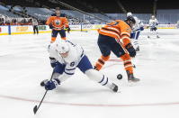 Edmonton Oilers' Tyson Barrie (22) and Toronto Maple Leafs' John Tavares (91) battle for the puck during first-period NHL hockey game action in Edmonton, Alberta, Monday, March 1, 2021. (Jason Franson/The Canadian Press via AP)