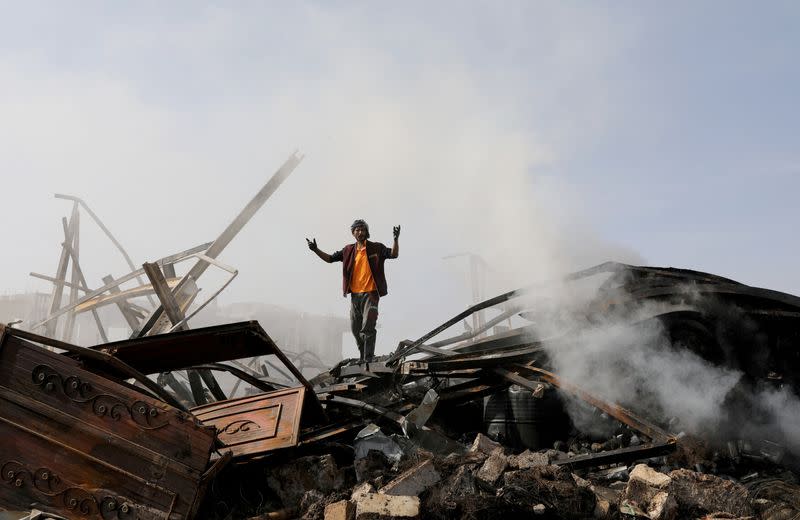 FILE PHOTO: A worker reacts as he stands on the wreckage of a vehicle oil and tires store hit by Saudi-led air strikes, in Sanaa