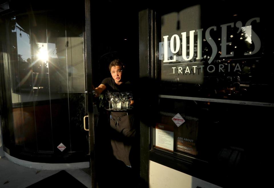 Server Battur Erdenebat carries drinks for customers at Louise's Trattoria on Larchmont Boulevard.