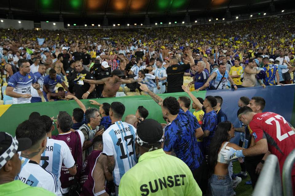 Players of Argentina try to calm the crowd after a fight between Brazilian and Argentinian fans in the stands prior to a qualifying soccer match for the FIFA World Cup 2026 at Maracana stadium in Rio de Janeiro, Brazil, Tuesday, Nov. 21, 2023. (AP Photo/Silvia Izquierdo)