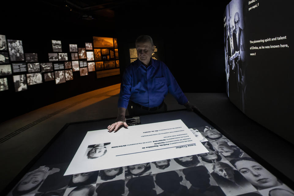 Jorge Tredler, 83, of Poland, who came to Brazil with his family in Feb. 1951 after taking refuge in Russia and other countries during the second World War, points to a photo of his mother Irena on an interactive table that tells the stories of thousands of people who took refuge in Brazil during the Holocaust, at the Holocaust Victims Memorial on its opening day to the public in Rio de Janeiro, Brazil, Thursday, Jan. 19, 2023. (AP Photo/Bruna Prado)