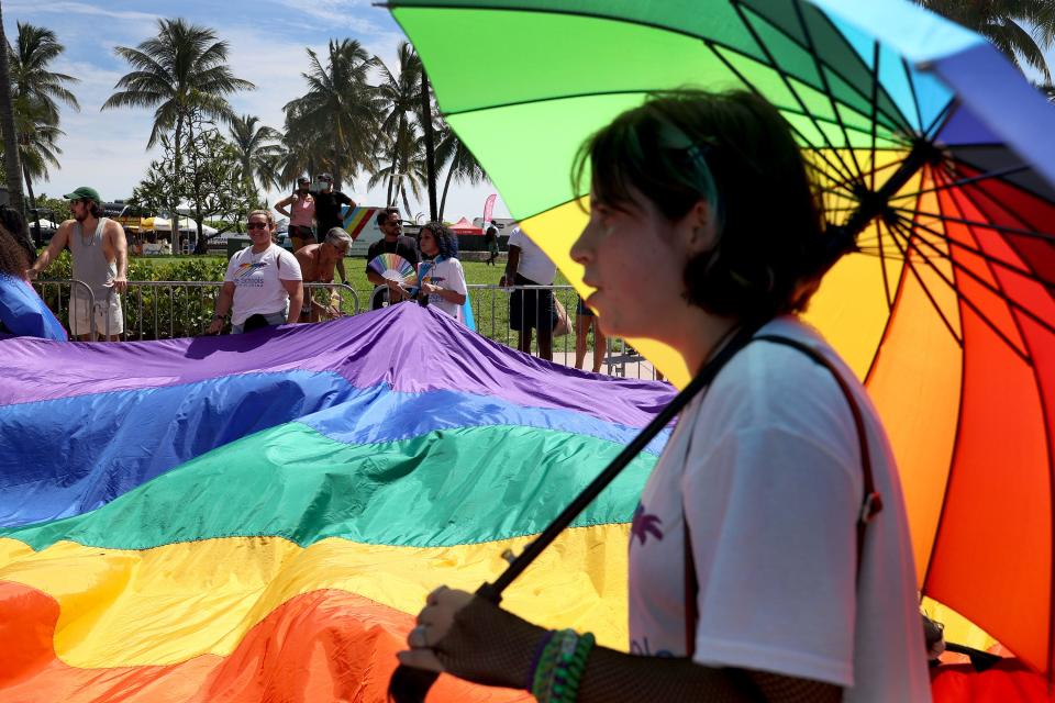 A person carries a rainbow umbrella at Miami Beach Pride.