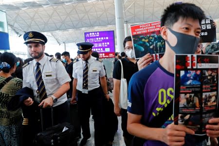 Pilots walk past anti-extradition bill protesters at a mass demonstration after a woman was shot in the eye during a protest at Hong Kong International Airport, in Hong Kong