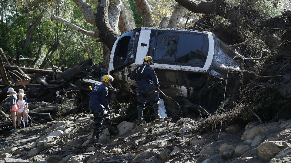 Members of the Los Angeles County Fire Department Search and Rescue crew work on a car trapped under debris from a mudslide in Montecito, California, on January 10, 2018. - Marcio Jose Sanchez/AP