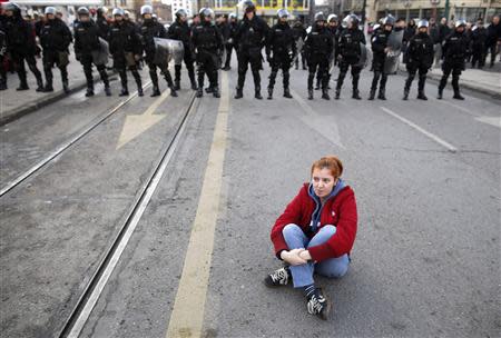 An anti-government protester sits on the ground in front of police during a demonstration in Sarajevo February 6, 2014. REUTERS/Dado Ruvic