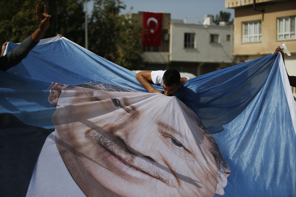 A man kisses a poster of Turkey's President Recep Tayyip Erdogan during show of support by about a dozen people for Turkey's operation in Syria, in the border town of Akcakale, Sanliurfa province, southeastern Turkey, on Monday, Oct. 14, 2019. Erdogan has criticized NATO allies which are looking to broaden an arms embargo against Turkey over its push into northern Syria. (AP Photo/Lefteris Pitarakis)