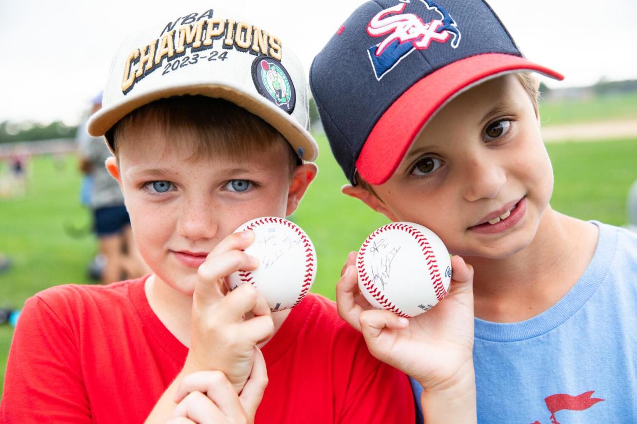 Two kids show off their autographed baseballs.