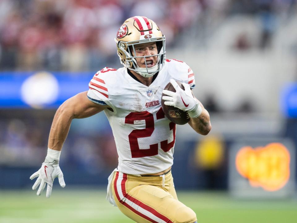 Christian McCaffrey runs with the ball during a 49ers game.