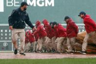 The Fenway Park grounds crew pulls out the tarp during a rain delay in the third inning of a baseball game between the Boston Red Sox and the Los Angeles Angels, Monday, April 17, 2023, in Boston. (AP Photo/Michael Dwyer)