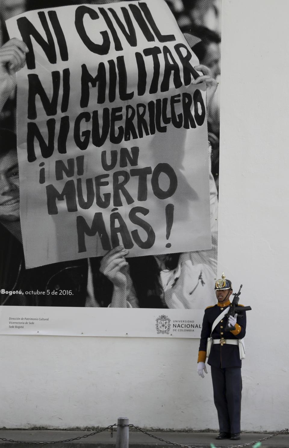A soldier stands guard next to a giant poster that reads in Spanish "Not one more dead civilian or Soldier, or guerrilla. Not one more death," in front of the Cloister of San Agustin in Bogota, Colombia, Thursday, Aug. 29, 2019. The top peace negotiator for the Revolutionary Armed Forces of Colombua, FARC, announced that he and a cadre of hardline supporters are taking up arms again, accusing President Ivan Duque of failing to uphold the accord that sought to end a half century of bloody fighting. (AP Photo/Fernando Vergara)