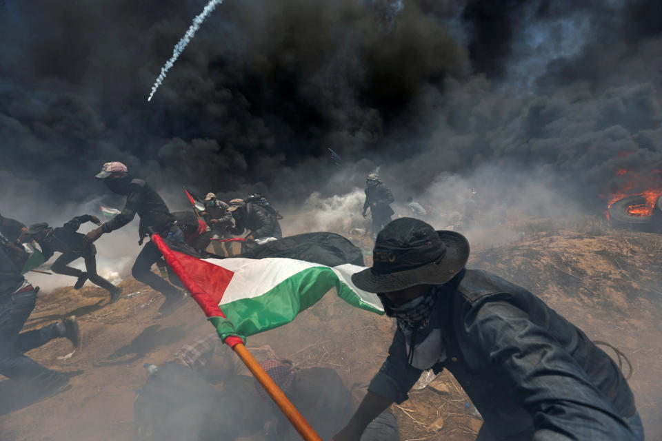 Palestinian demonstrators run for cover from Israeli fire and tear gas.