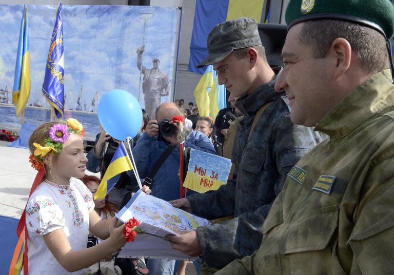 A girl wearing Ukrainian traditional costume gives drawings to soldiers during the celebrations marking the city day on September 20, 2014 in Mariupol