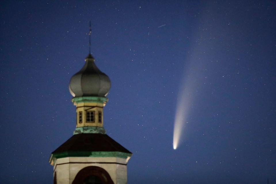 The comet Neowise or C/2020 F3 is seen behind an Orthodox church over the Turets, Belarus, 110 kilometers (69 miles) west of capital Minsk, early Tuesday, July 14, 2020.