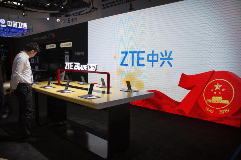 FILE - In this Thursday, Oct. 31, 2019, file photo, a man looks at products from Chinese technology firm ZTE near a screen showing a display commemorating the 70th anniversary of the founding of China at the PT Expo in Beijing. The Senate has passed a bill that provides $1 billion for small telecom providers to replace equipment in their networks that's made by China's Huawei and ZTE. It now goes to President Donald Trump. Huawei and ZTE did not immediately reply to a request for comment, Thursday, Feb. 27, 2020. (AP Photo/Mark Schiefelbein, File)