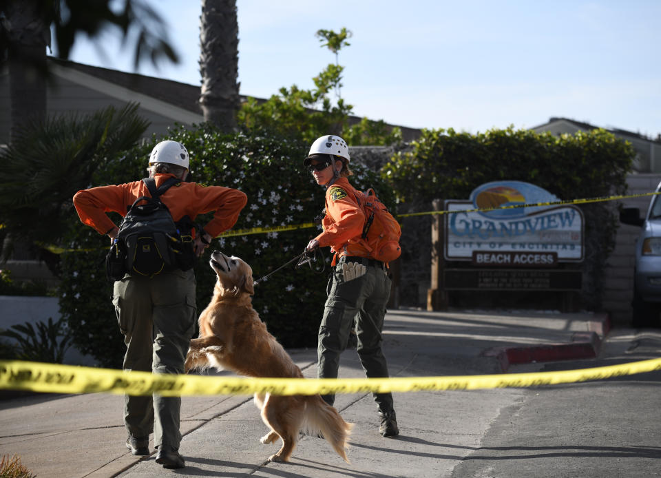 Search and rescue personnel head down to the site of a cliff collapse at a popular beach Friday, Aug. 2, 2019, in Encinitas, Calif. At least one person was reportedly killed, and multiple people were injured, when an oceanfront bluff collapsed Friday at Grandview Beach in the Leucadia area of Encinitas, authorities said. (AP Photo/Denis Poroy)