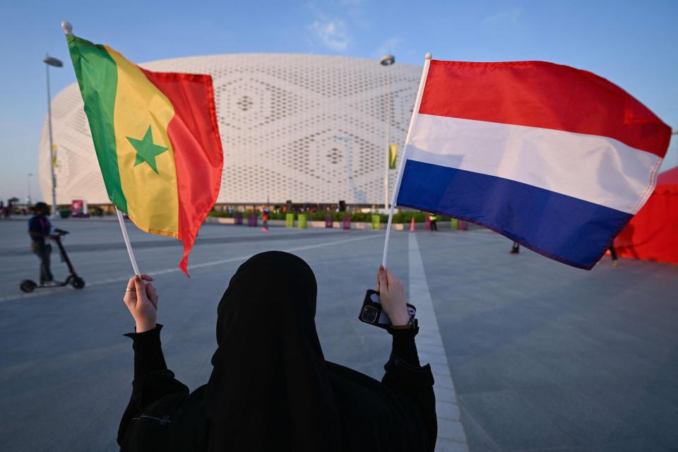 A woman holds up flags of Senegal and the Netherlands ahead of the Group A match (AFP via Getty Images)