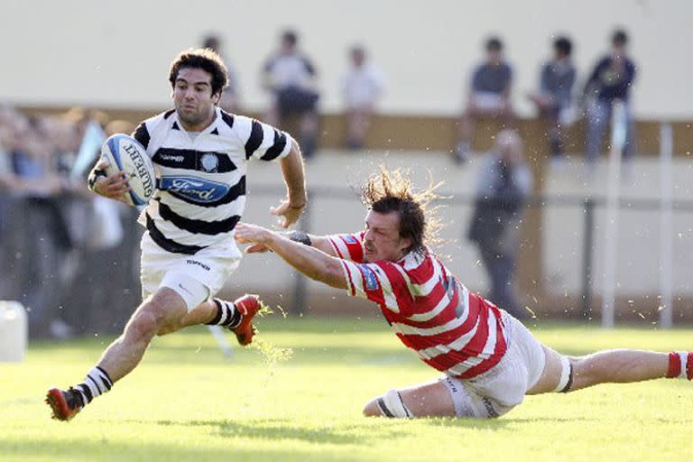 Casi haciendo equilibrio para no pisar la línea de touch, Agustín Figuerola se escapa de Jaime Arocena