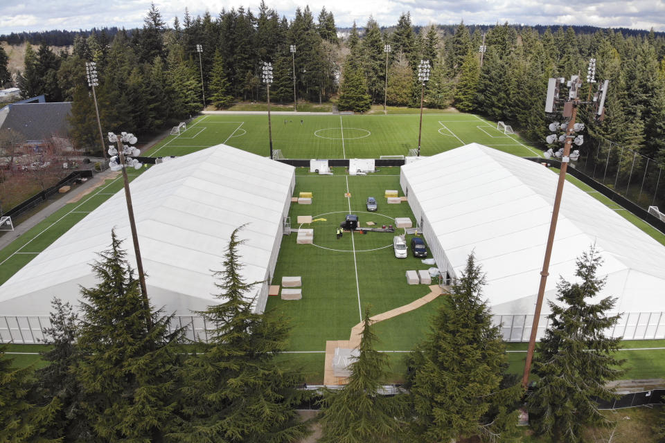 In this photo taken Tuesday, March 24, 2020, two massive temporary buildings meant for use as a field hospital for coronavirus patients stand together on a soccer field in the Seattle suburb of Shoreline, Wash. With U.S. hospital capacity stretched thin, hospitals around the country are scrambling to find space for a coming flood of COVID-19 patients, opening older closed hospitals and repurposing other buildings. (AP Photo/Elaine Thompson)