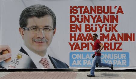 A man runs past by an election billboard with a picture of Turkish Prime Minister Ahmet Davutoglu and a slogan that reads: "We are building World's biggest airport in Istanbul. They speak. AK Party does", in Istanbul's financial district of Gayrettepe, Turkey, May 25, 2015. REUTERS/Murad Sezer