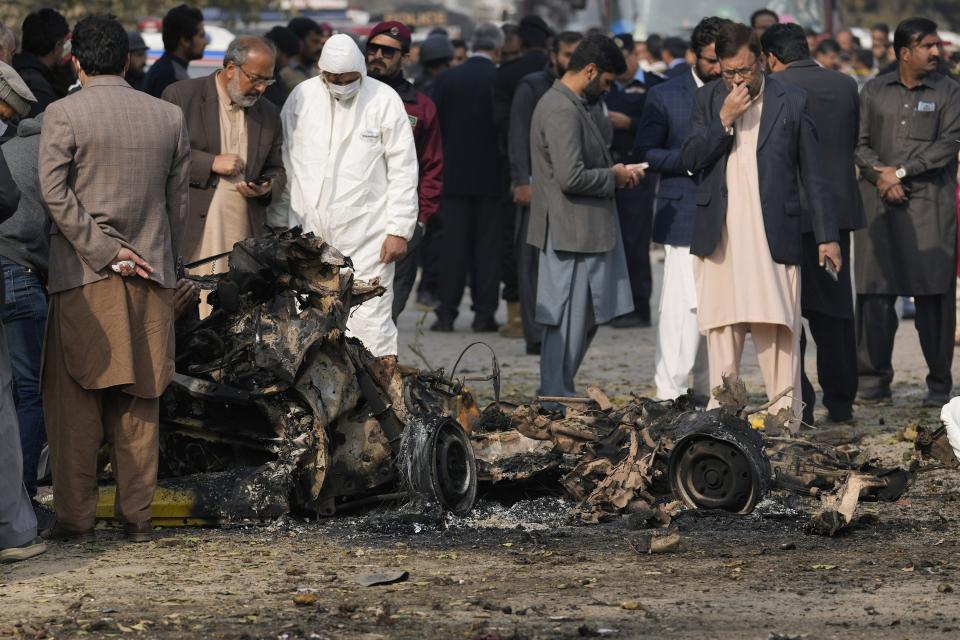 Investigators collect evidence from the wreckage of a car at the site of bomb explosion, in Islamabad, Pakistan, Friday, Dec. 23, 2022. A powerful car bomb detonated near a residential area in the capital Islamabad on Friday, killing some people, police said, raising fears that militants have a presence in one of the country's safest cities. (AP Photo/Anjum Naveed)