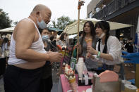 A local resident tries out ice-cream crepe at a weekend open air market in Beijing on Saturday, Aug. 8, 2020. As the coronavirus outbreak comes under control in the Chinese capital, normal life is slowing returning albeit with the requisite masks. (AP Photo/Ng Han Guan)