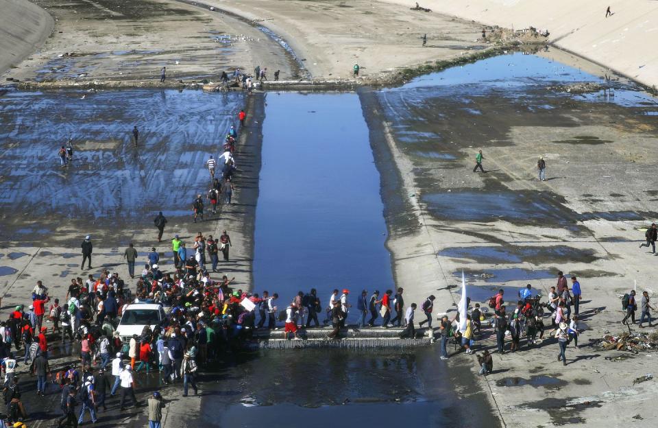 <p>Migrants cross the nearly dry Tijuana River as they make their way around a police blockade toward the El Chaparral port of entry on November 25, 2018 in Tijuana, Mexico.</p>