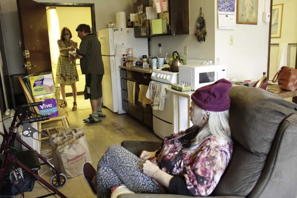 FILE - Joel Aslin accepts groceries for his neighbor, Karen Colby, from a volunteer with the nonprofit Store to Door on July 22, 2021, in Portland, Ore. Colby spent 10 days in the hospital with complications from heat stroke after nearly dying during a record-smashing heat wave that hit the Pacific Northwest with temperatures of up to 116 F. As heat waves fueled by climate change arrive earlier, grow more intense and last longer, people over 60 who are more vulnerable to high temperatures are increasingly at risk of dying from heat-related causes. (AP Photo/Gillian Flaccus,File)