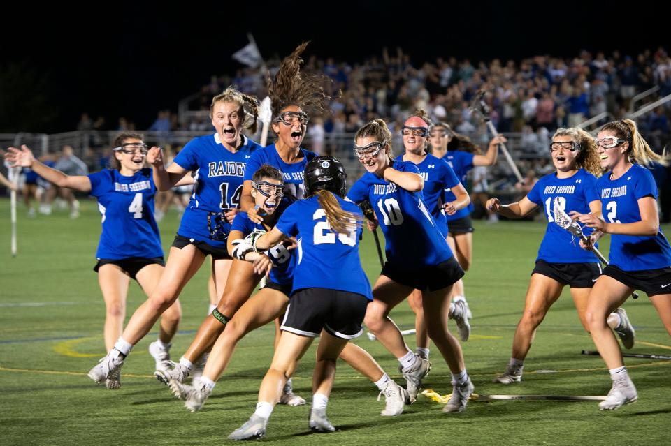 Members of the Dover-Sherborn varsity girls lacrosse team run to junior goalkeeper Kathryn Mahoney after defeating Manchester-Essex 10-7 in the Division 4 state championship game at Babson College in Wellesley, June 21, 2022.  