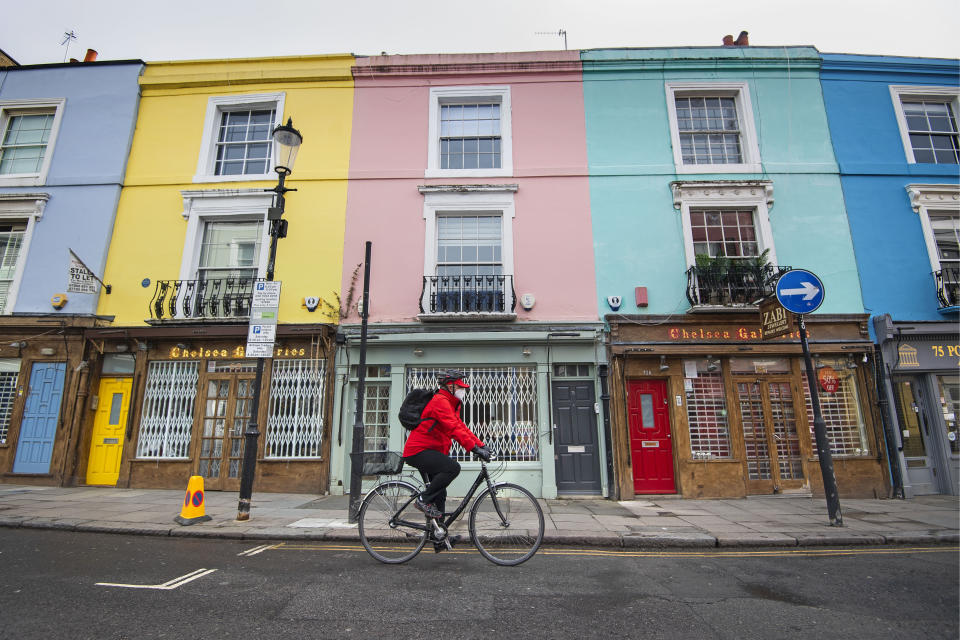 A cyclist wearing a face mask rides past closed up shops on Portobello Road in West London as the UK continues in lockdown to help curb the spread of the coronavirus.