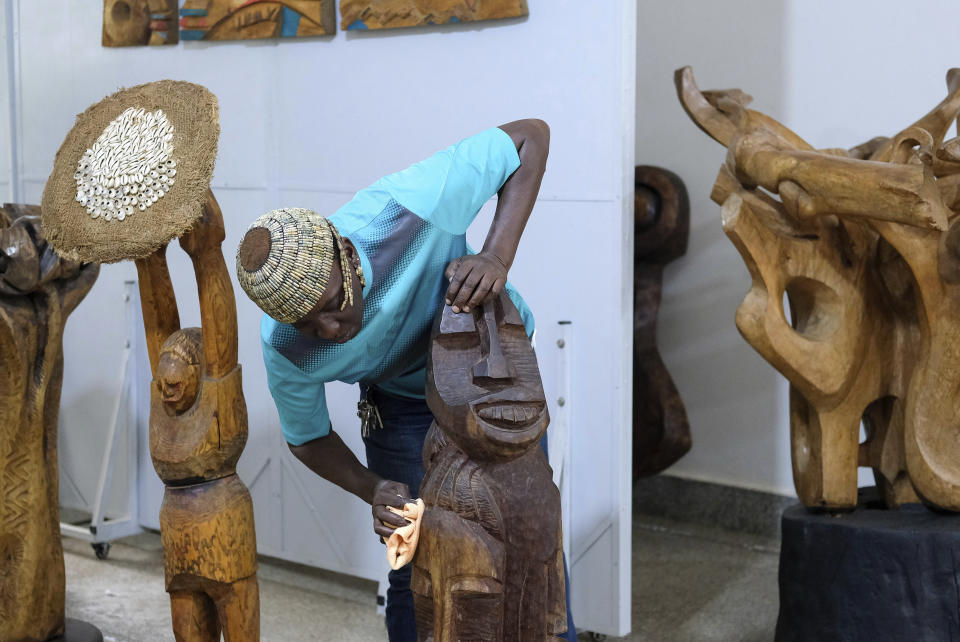 Lilian Nabulime dusting sculpture pieces at her workshop in Kyanja, a suburb in Kampala City, Wednesday Nov. 29 2023.. Lilian Nabulime hasn't forgotten the time in the 1990s when the Ugandan capital had just one commercial art gallery, a small space that emerging artists struggled to get into. Now there are at least six in Kampala, including one whose curators recently exhibited the sculptor's contrarian work. (AP Photo/Hajarah Nalwadda.)