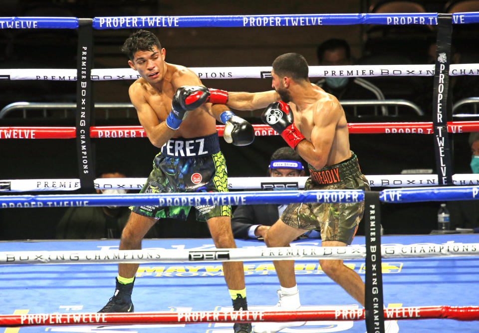 Jerry Perez, left, tries to avoid a punch from Joshua Zuniga during a junior lightweight boxing bout Saturday, Oct. 31, 2020, in San Antonio. (AP Photo/Ronald Cortes)