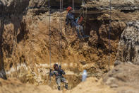 Rescuers from the Guatemalan Army descend into a sinkhole in Villa Nueva, Guatemala, Tuesday, Sept. 27, 2022. Search efforts continue for a mother and daughter who disappeared when their vehicle was swallowed by the massive sinkhole. (AP Photo/Moises Castillo)