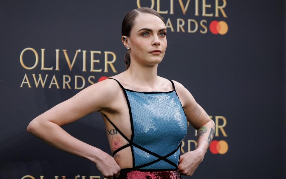 Delevingne with short hair and strappy shiny top