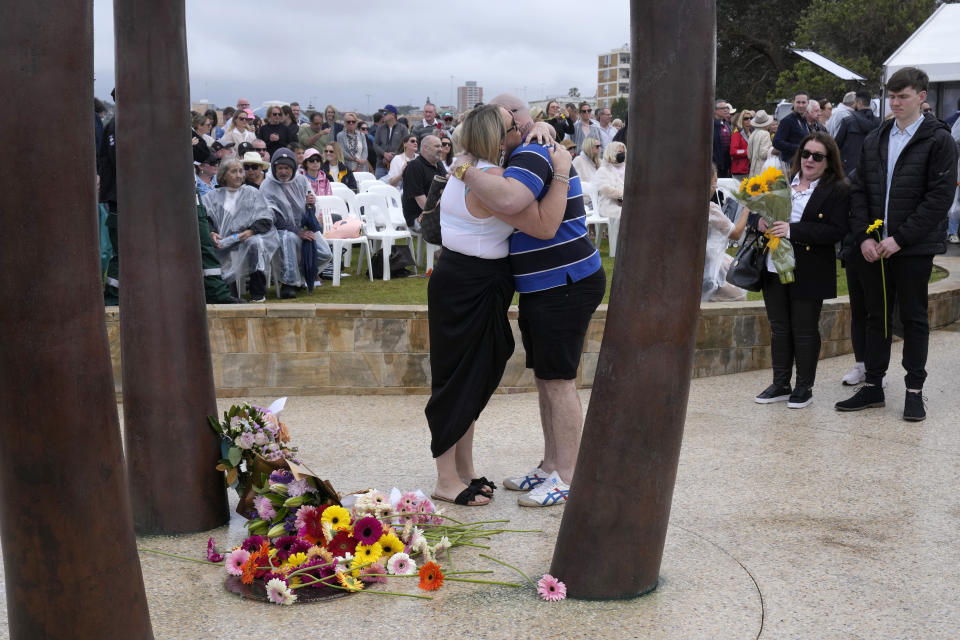 A couple embrace after laying a flower tribute during a memorial ceremony in Sydney, Australia, Wednesday, Oct. 12, 2022, honoring the victims of the 2002 Bali bombing that killed 202 people, mostly foreign tourists, including 88 Australians, and seven Americans. (AP Photo/Rick Rycroft)